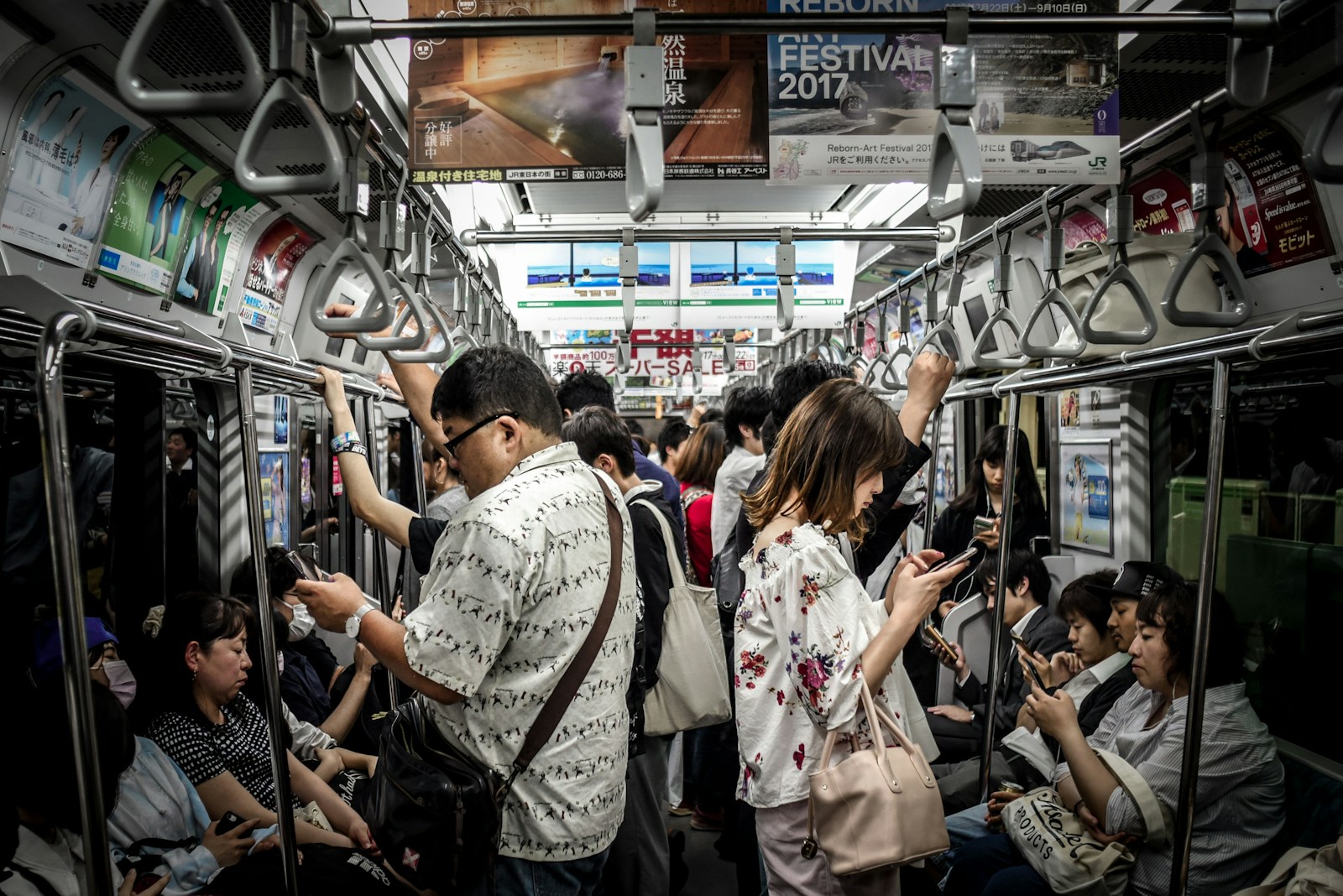 Commuters on a crowded Tokyo train looking at their smartphones